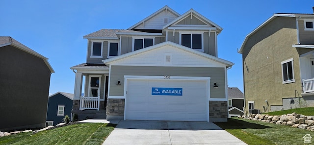 craftsman inspired home featuring a garage, concrete driveway, a front yard, and stone siding