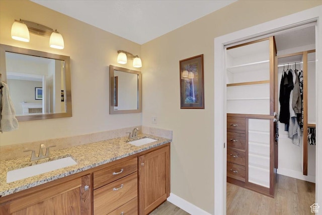 243 Eastridge E, Logan, UT 84321 - full bathroom with baseboards, a walk in closet, a sink, and wood finished floors