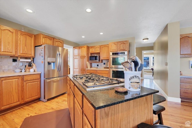 243 Eastridge E, Logan, UT 84321 - kitchen with a breakfast bar, light wood finished floors, stainless steel appliances, tasteful backsplash, and a kitchen island