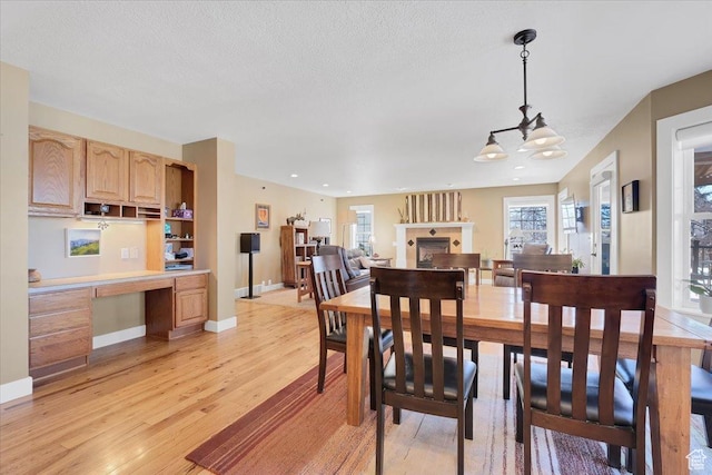 243 Eastridge E, Logan, UT 84321 - dining space with a fireplace, built in desk, light wood-style floors, a textured ceiling, and baseboards