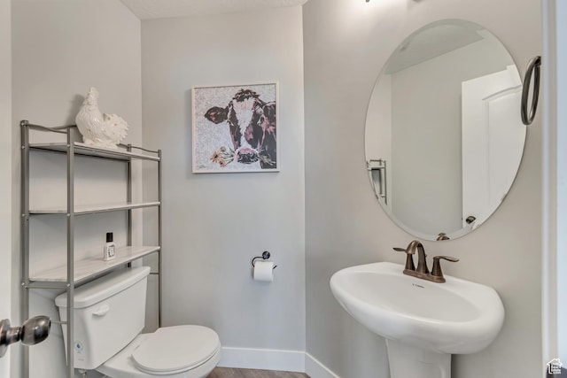 bathroom featuring baseboards, a sink, toilet, and wood finished floors