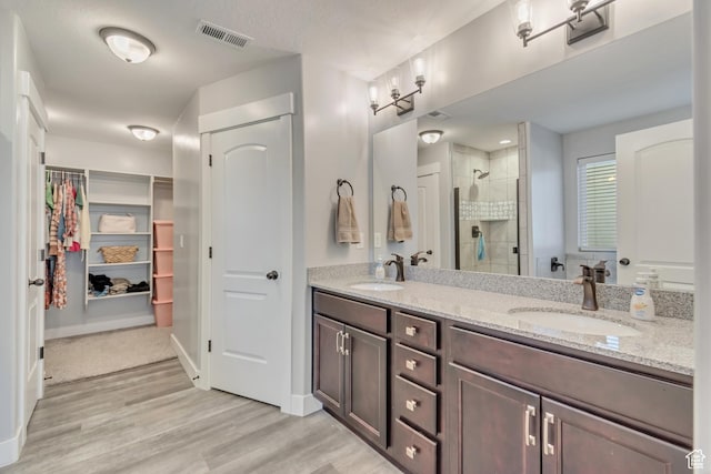full bath featuring a stall shower, visible vents, a sink, and wood finished floors