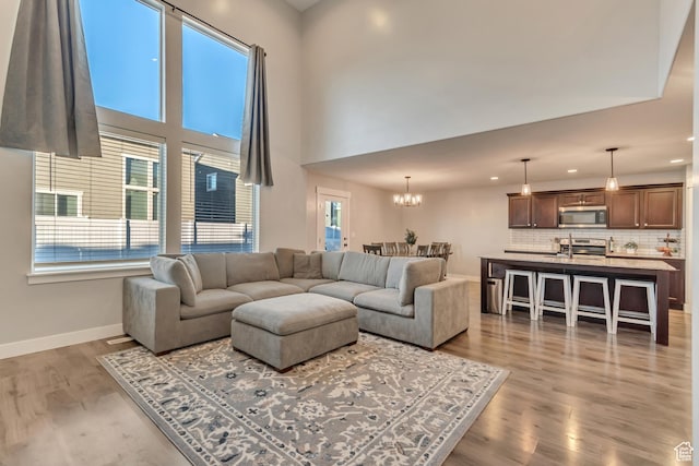 living room featuring light wood-type flooring, a towering ceiling, baseboards, and a wealth of natural light