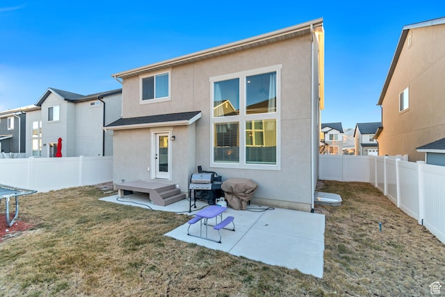 back of house featuring a yard, a fenced backyard, a patio area, and stucco siding