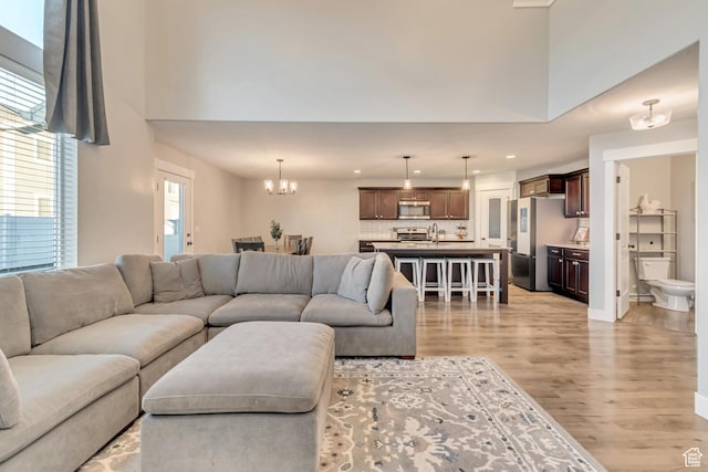 living area with a chandelier, a high ceiling, light wood-type flooring, and recessed lighting