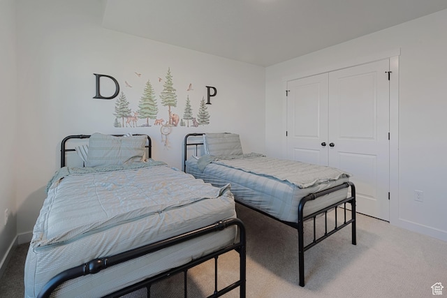 bedroom with baseboards, a closet, and light colored carpet