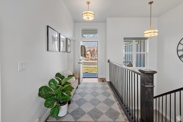 corridor with a healthy amount of sunlight, baseboards, and an upstairs landing