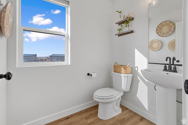 half bathroom with a sink, wood finished floors, toilet, and baseboards
