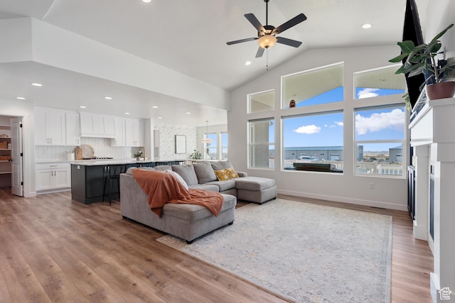 living room with baseboards, ceiling fan, light wood-style floors, high vaulted ceiling, and recessed lighting