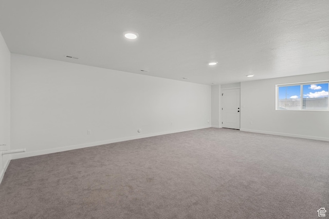 carpeted empty room featuring a textured ceiling, recessed lighting, and baseboards
