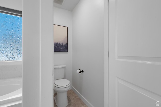 bathroom with visible vents, toilet, a bath, baseboards, and tile patterned floors