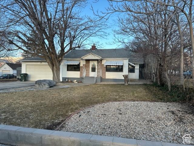 143 N 150 W, Tooele, UT 84074 - view of front facade with a garage, driveway, a chimney, and a front yard