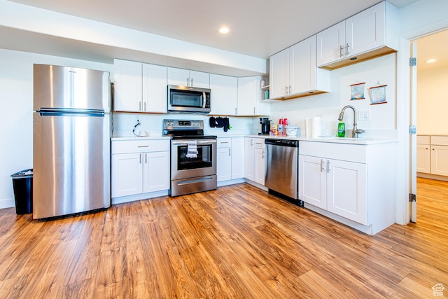 kitchen featuring light wood-style floors, stainless steel appliances, a sink, and light countertops