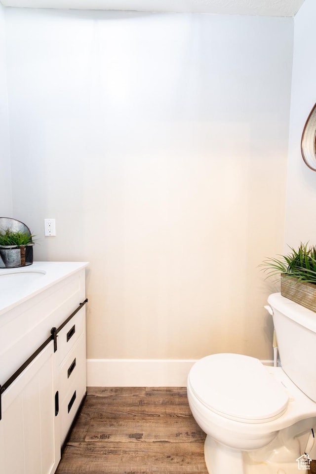 bathroom featuring baseboards, vanity, toilet, and wood finished floors