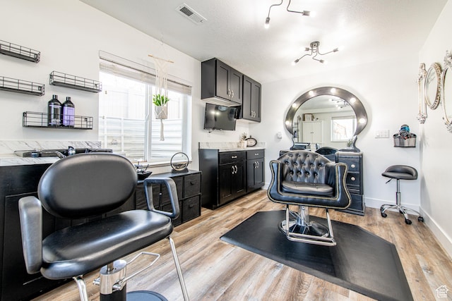 interior space with visible vents, baseboards, light wood-style flooring, dark cabinets, and light countertops