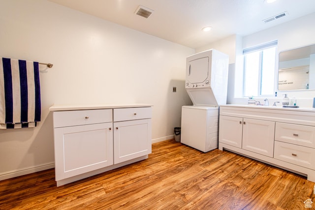 laundry room featuring baseboards, light wood-style flooring, visible vents, and stacked washer / drying machine