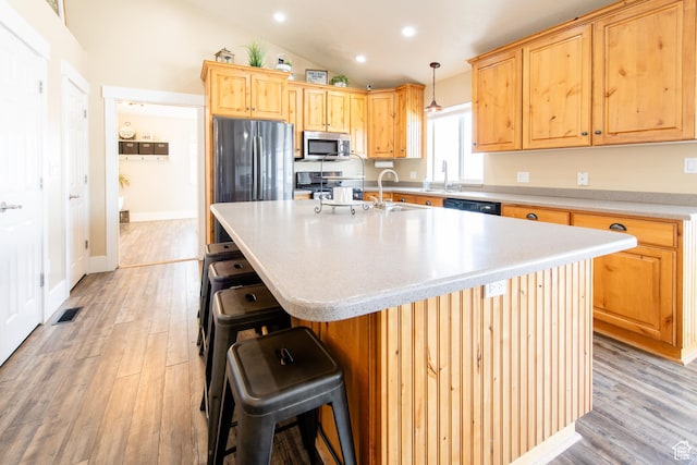 kitchen featuring visible vents, appliances with stainless steel finishes, vaulted ceiling, light wood-type flooring, and a sink