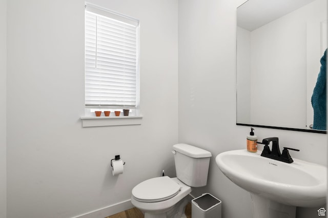 bathroom with a sink, toilet, and baseboards