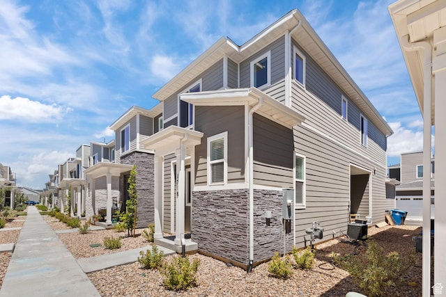 view of property exterior featuring stone siding, a residential view, and cooling unit