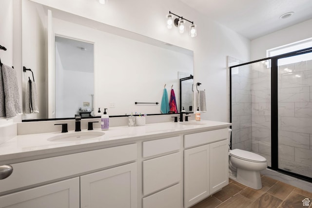 full bath with toilet, a shower stall, double vanity, and a sink