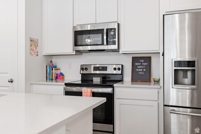 kitchen with stainless steel appliances, light countertops, and white cabinetry