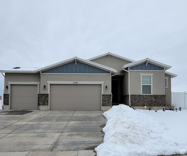 view of front of house with stucco siding, stone siding, board and batten siding, concrete driveway, and an attached garage