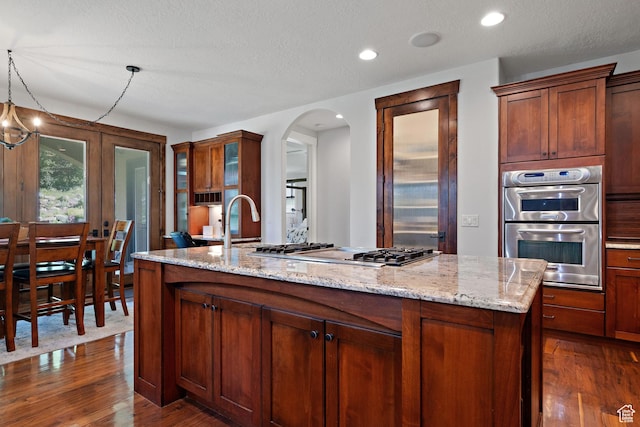 267 E Lucky Star Way, Farmington, UT 84025 - kitchen featuring stainless steel appliances, dark wood-style flooring, arched walkways, an island with sink, and light stone counters