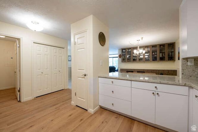 560 E S Temple N Pl 102, Salt Lake City, UT 84102 - bar area with light wood finished floors, a chandelier, baseboards, a textured ceiling, and backsplash