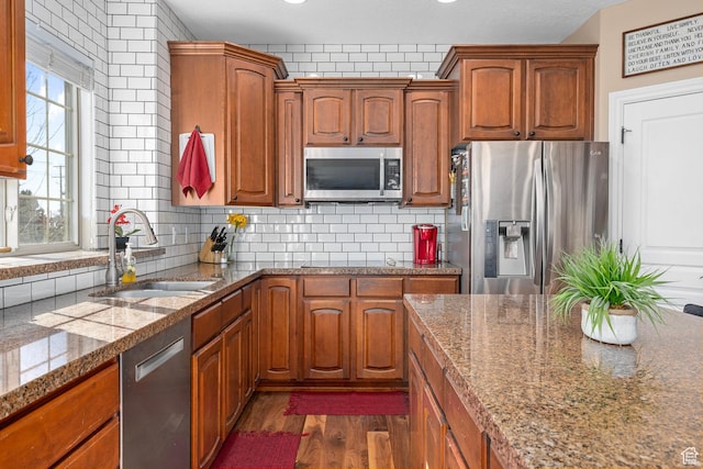 kitchen featuring appliances with stainless steel finishes, a sink, and brown cabinetry
