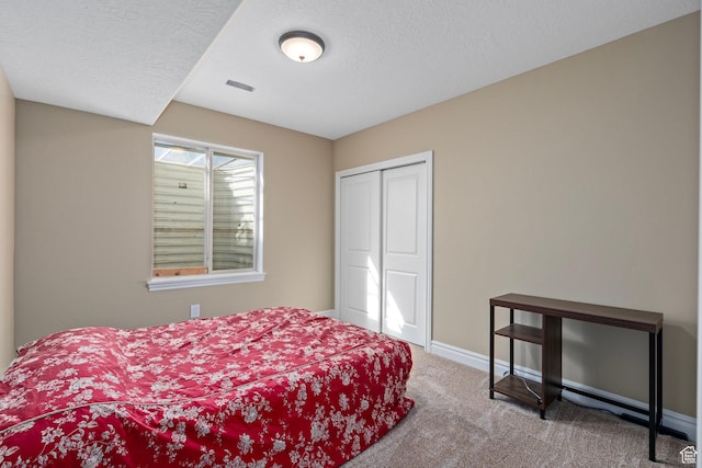 carpeted bedroom featuring baseboards, a closet, and a textured ceiling