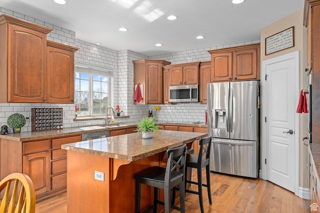 kitchen featuring stainless steel appliances, a sink, a kitchen island, recessed lighting, and a kitchen breakfast bar