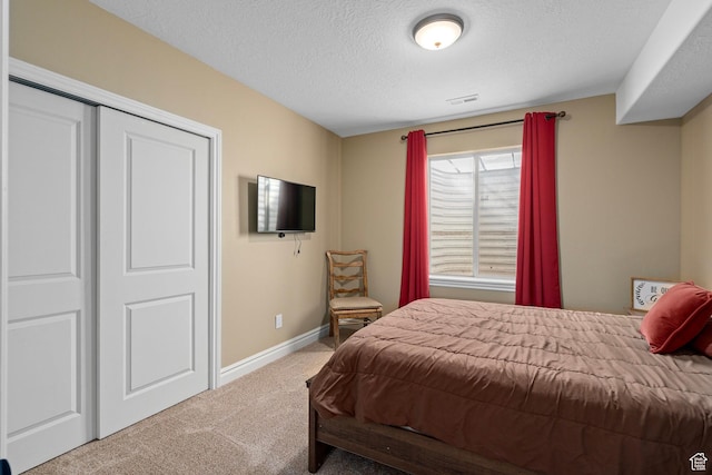 bedroom featuring carpet flooring, a textured ceiling, baseboards, and a closet