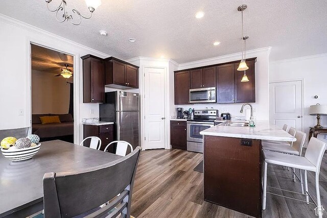 1042 W 500 S, Provo, UT 84601 - kitchen featuring dark brown cabinetry, a peninsula, a breakfast bar, dark wood-style flooring, and appliances with stainless steel finishes