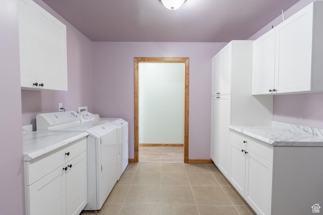 laundry room with cabinet space, light tile patterned floors, baseboards, and washer and clothes dryer