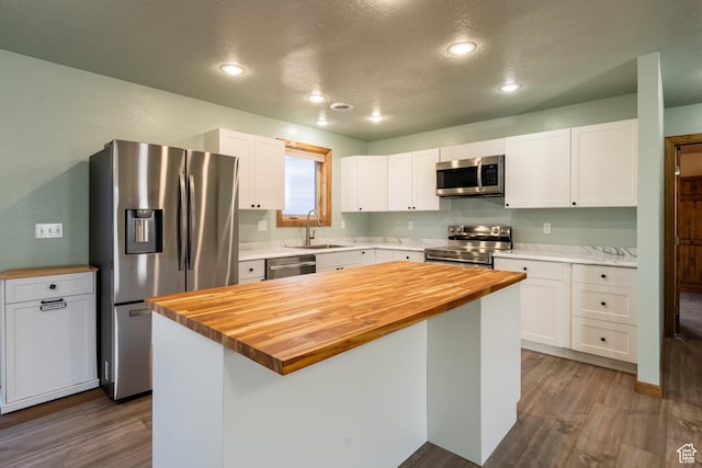 kitchen featuring dark wood finished floors, stainless steel appliances, butcher block counters, white cabinets, and a sink