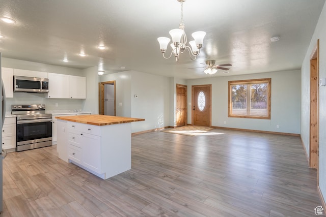 kitchen featuring light wood finished floors, wood counters, appliances with stainless steel finishes, and white cabinets