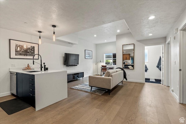 living area with recessed lighting, baseboards, light wood-style flooring, and a textured ceiling