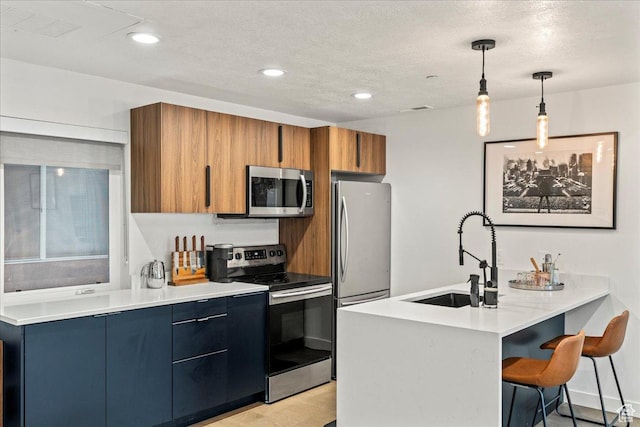 kitchen with brown cabinets, stainless steel appliances, light countertops, a sink, and a kitchen breakfast bar