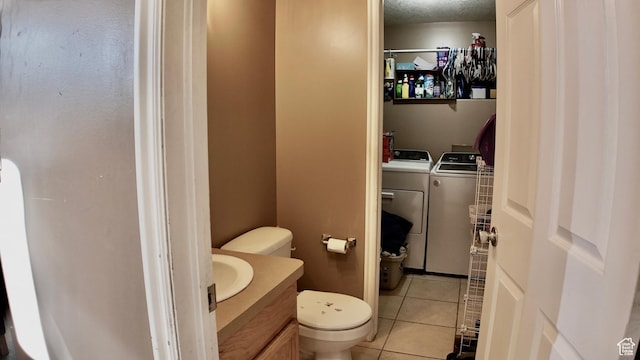bathroom featuring toilet, vanity, washer and clothes dryer, and tile patterned floors