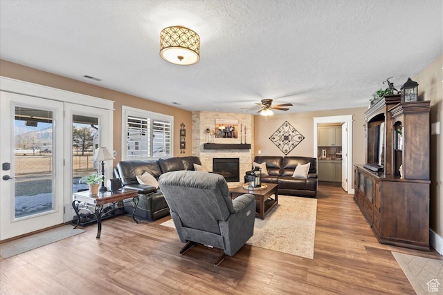 1004 W 4050 S, Riverdale, UT 84405 - living room featuring light wood-style floors, a ceiling fan, a textured ceiling, and a stone fireplace