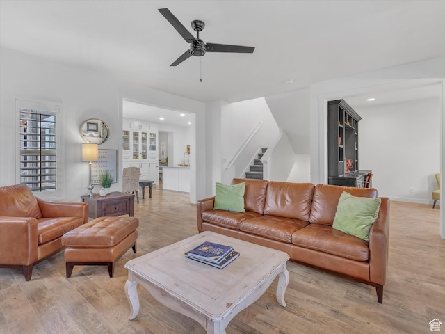 living area featuring stairs, light wood-type flooring, a ceiling fan, and recessed lighting