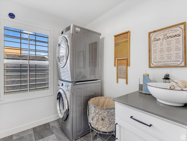 clothes washing area featuring laundry area, baseboards, and stacked washer / drying machine