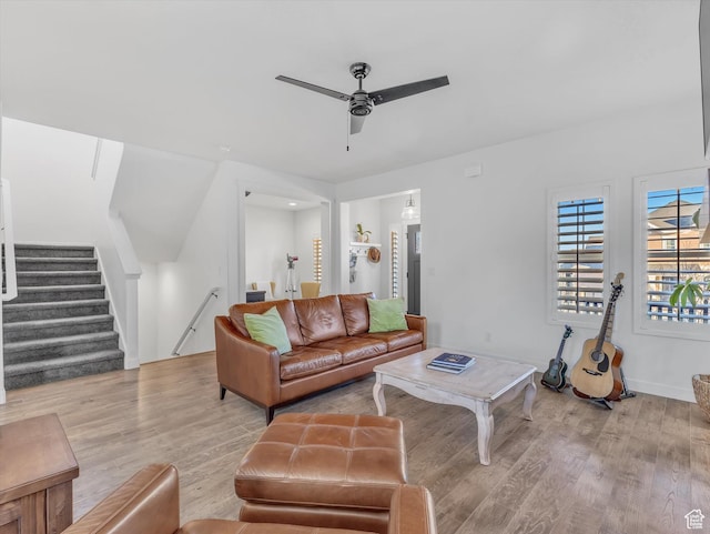 living area with stairway, a ceiling fan, and wood finished floors
