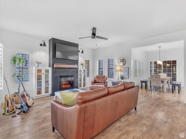 living area featuring light wood-style floors, a fireplace, and a ceiling fan