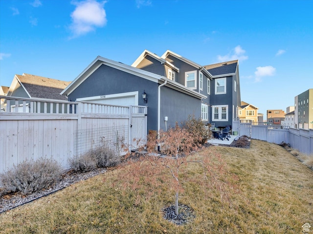 view of side of property with a fenced backyard, a residential view, an attached garage, a yard, and stucco siding