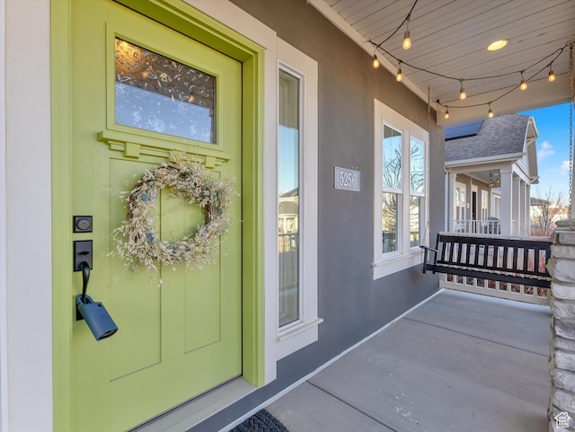 entrance to property with a porch and stucco siding