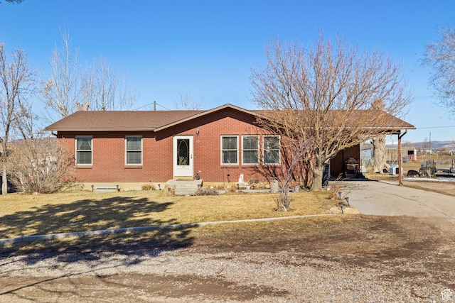 ranch-style house featuring a front lawn, an attached carport, concrete driveway, and brick siding