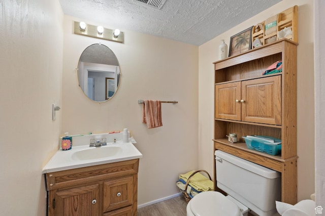 879 E Main St, Mount Pleasant, UT 84647 - bathroom with visible vents, toilet, wood finished floors, a textured ceiling, and vanity