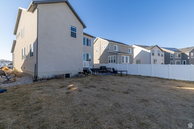 back of property with a lawn, fence, a residential view, and stucco siding