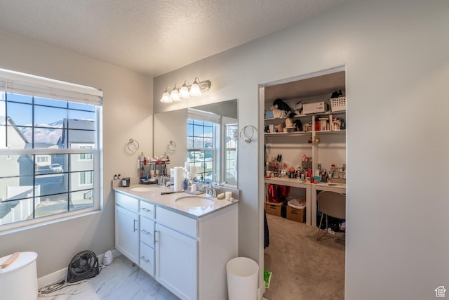 bathroom with a sink, a textured ceiling, baseboards, and double vanity